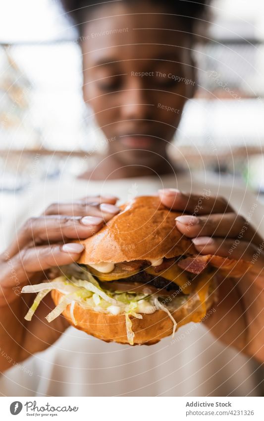 Crop black woman eating appetizing hamburger enjoy hungry delicious fast food junk food tasty appetite unhealthy calorie casual fresh yummy young lunch meal