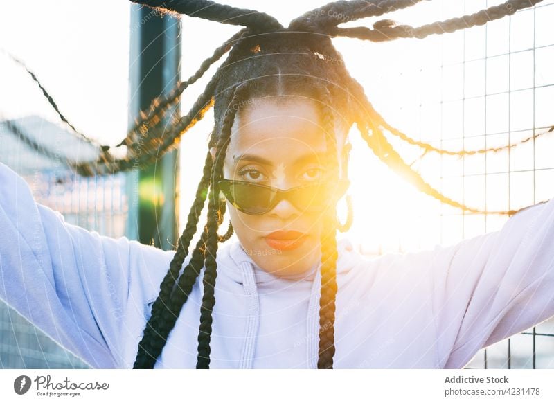 Cool black woman with Afro braids on street in sunshine afro fashion sunglasses cool street style individuality portrait self confident african american ethnic
