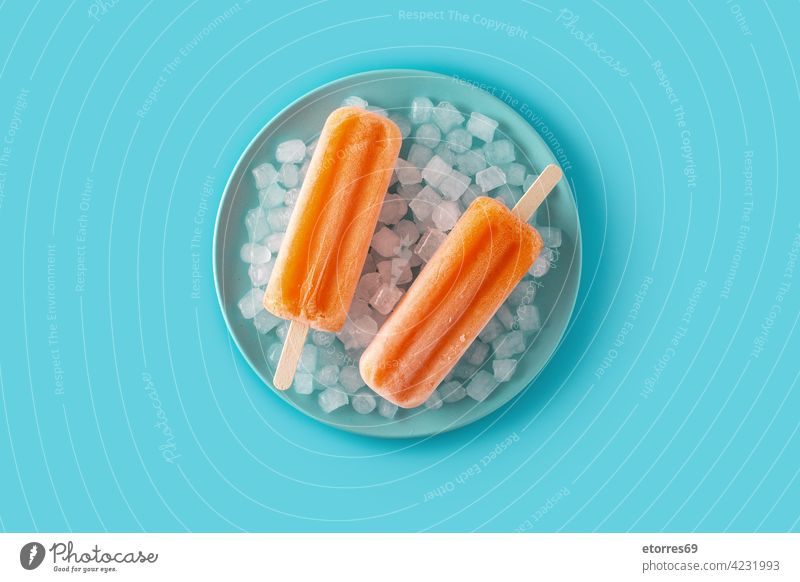 Orange popsicles on blue plate background cake cold colorful cool cream dessert flavor food fresh frosty frozen fruit homemade ice ice cream iced juice lolly