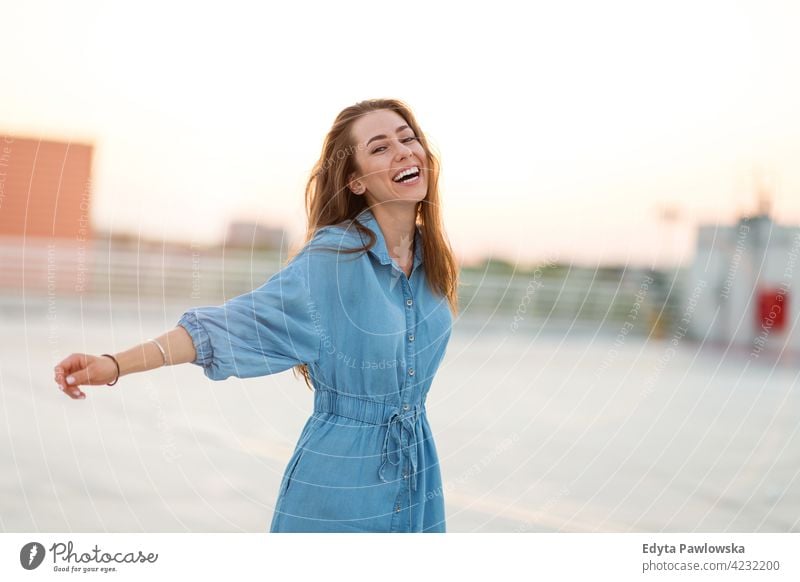 Portrait of an young woman on a rooftop enjoying sunset confident smiling female attractive beautiful young adult positive content standing lifestyle happy