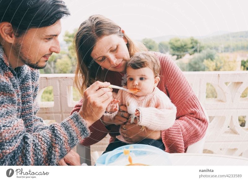 Real family sharing the first food of their baby real eating together complementary feeding mom dad childcare puree cream outdoors babyhood parenthood