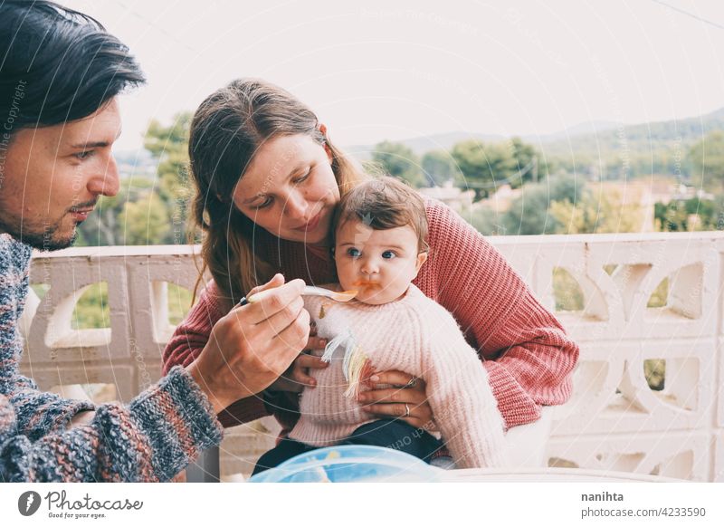 Real family sharing the first food of their baby real eating together complementary feeding mom dad childcare puree cream outdoors babyhood parenthood
