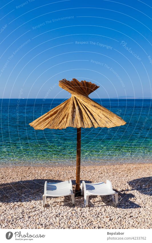 Straw umbrella in the beautiful Oprna beach in the Krk island oprna wave croatia sea summer krk sand summertime resort adriatic blue bathers tan tanning