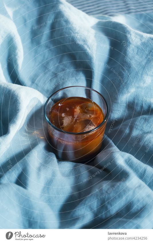 Top view of glass with ice coffee with vegan milk on blue linen blanket delicious black drink aroma fresh brown beverage caffeine cold cup mocha arabica frozen