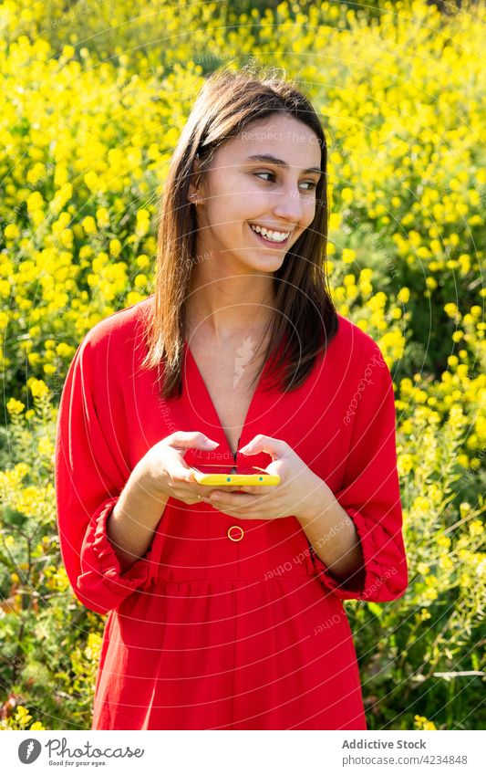 Smiling woman chatting on smartphone in summer field smile free time weekend countryside portrait using gadget device cellphone pastime text messaging internet