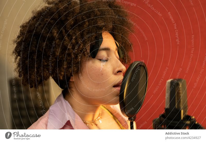 African American vocalist singing song into mic in recording studio singer microphone music professional woman pop filter sound melody afro hairstyle instrument