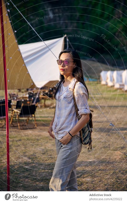 Asian female having a relaxing time in camping area woman tent model Chinese ethnic one person confident enjoy sunny nature grass sunglasses leisure focus
