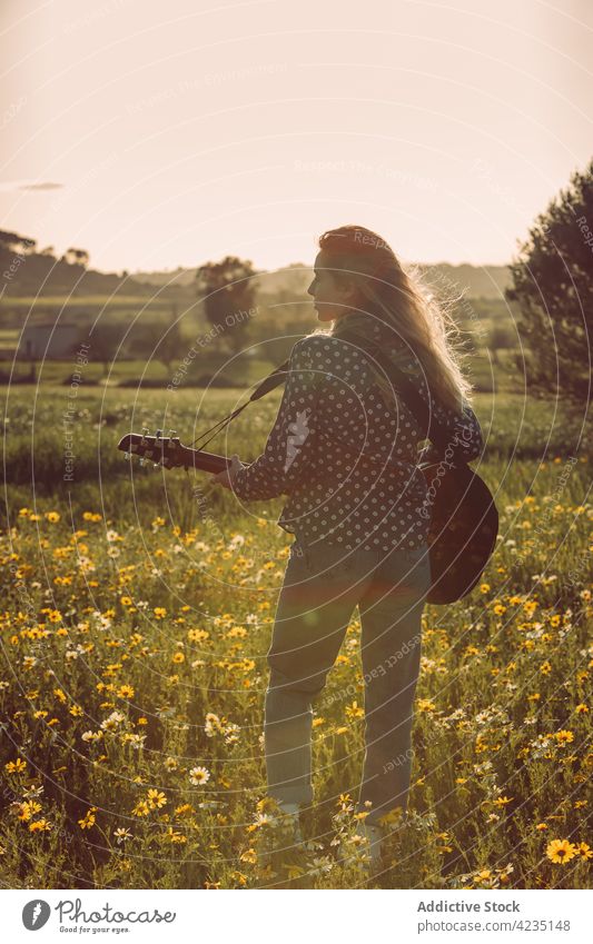Anonymous female playing guitar on nature woman summer countryside hipster musician dreamer summertime thoughtful lifestyle romantic stand meadow vacation