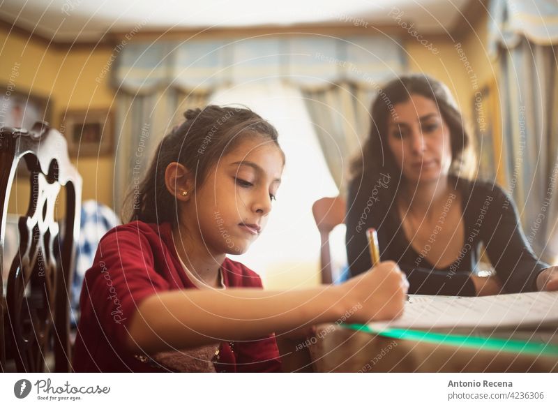 Mother and daughter doing homework home school class education child learning indoors mother mom parent caregiver woman female children kid caucasian two young