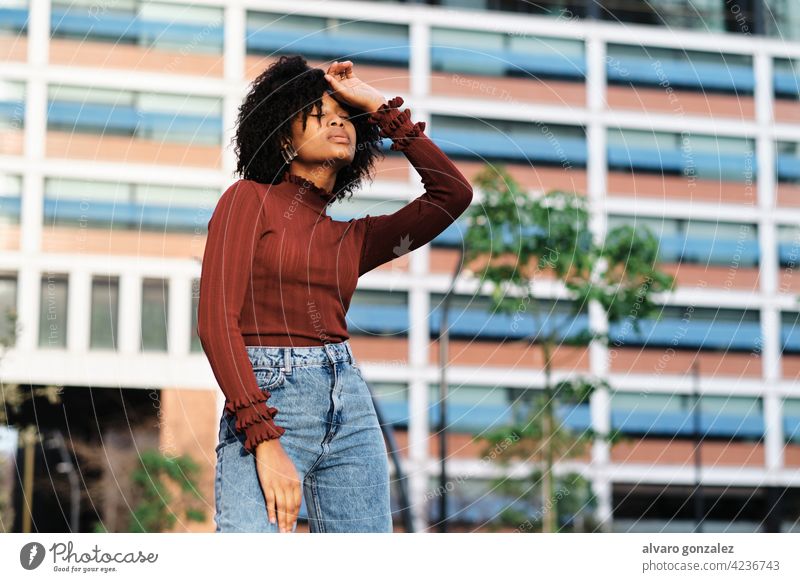 Afro woman standing outdoors on the street. young afro black urban portrait fashion city curly hair walking clothes outside background style female african