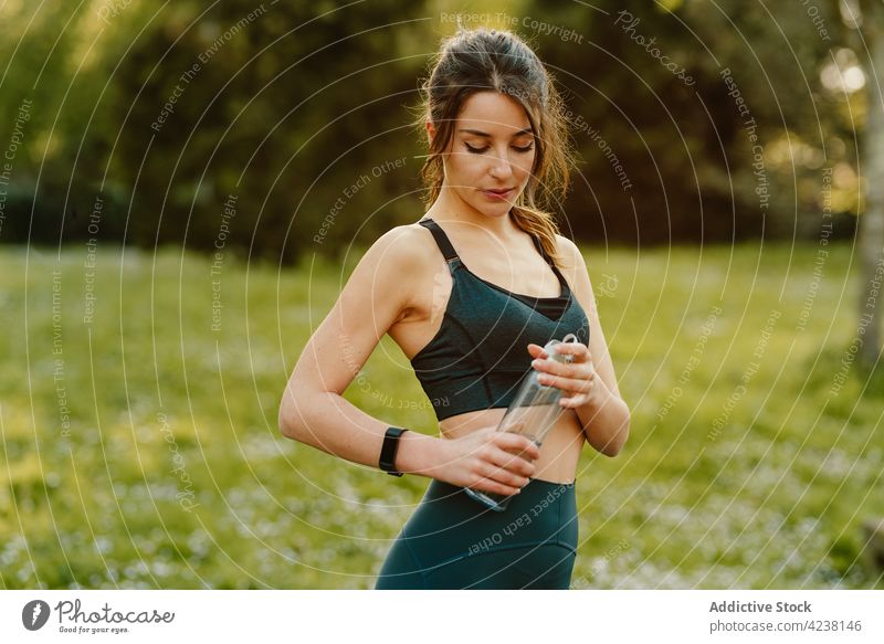 Athlete drinking water in sunshine athlete bottle smart watch heartbeat check up sport break woman using device meadow sportswoman rate workout training