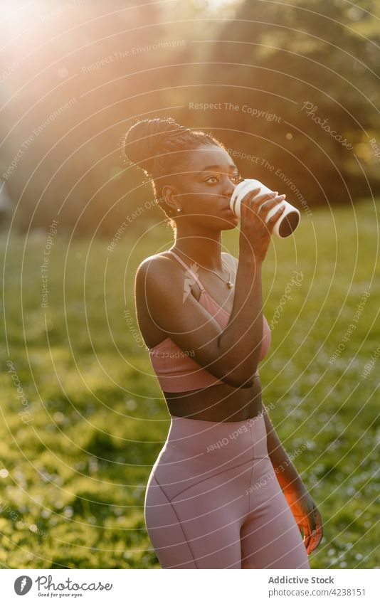 Black sportswoman with cup of drink in park athlete fit sunset beverage evening female ethnic black african american training enjoy sportswear summer break