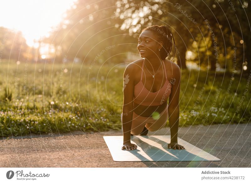 Black sportswoman training in park at sunset plank exercise balance abs workout fit female ethnic black african american athlete sportswear wellbeing abdomen