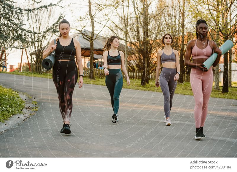Group of sportswomen walking along road together group athlete fit park training friend summer female black african american multiracial multiethnic diverse