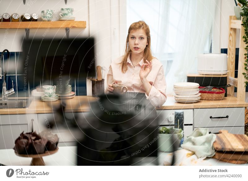 Vlogger speaking against photo camera in house kitchen vlogger record video culinary blog social media woman using gadget device smartphone multimedia explain