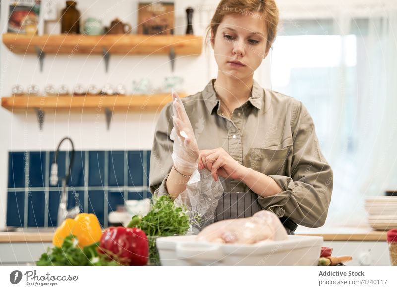 Crop woman putting on disposable gloves while cooking in kitchen put on pepper chicken culinary recipe portrait transparent vegetable vitamin bright herb sprig