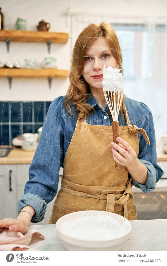 Cheerful woman with frosting on whisk in kitchen cream sweet cheerful cook culinary recipe home portrait smile homemade bowl utensil content charming process