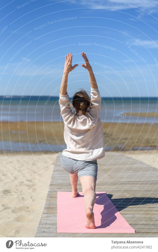 Woman doing yoga poses on beach woman health relaxation balance wellbeing mental health body asana meditation lifestyle practice sea sunny linen person exercise