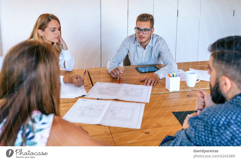 Businesspeople in a work meeting looking at construction drawings businesspeople architect teamwork office wooden table house plans talking project architecture