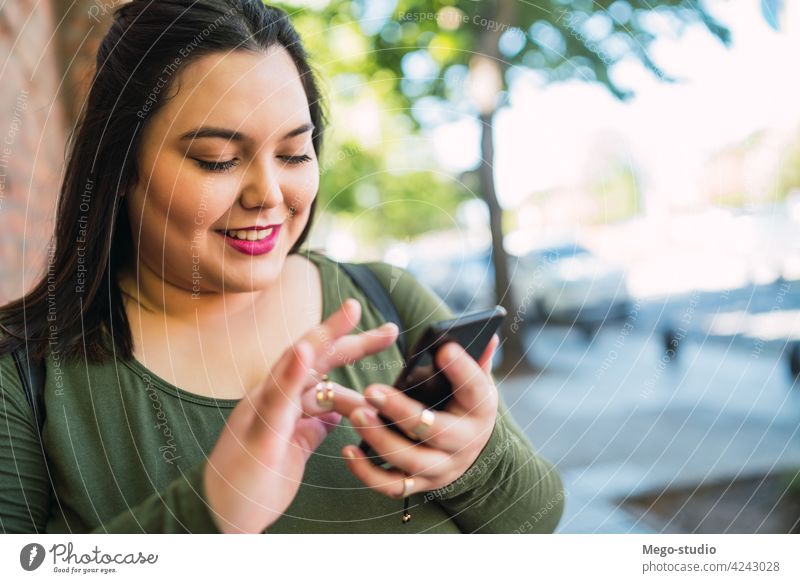 Young plus size woman using her mobile phone. plus-size street smartphone city people urban cellphone female text young sms message outdoor adult online