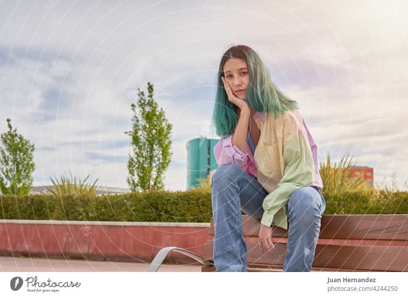 young girl with turquoise hair sitting on a bench pensive thinking expression one person emotion lonely relax relaxation introverted emotional ethnicity