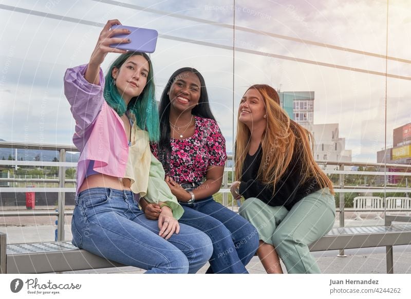 group of multiethnic girls taking a selfie with smartphone happy telephone smart phone cellphone caucasian hispanic afro ethnicity friendship together smile