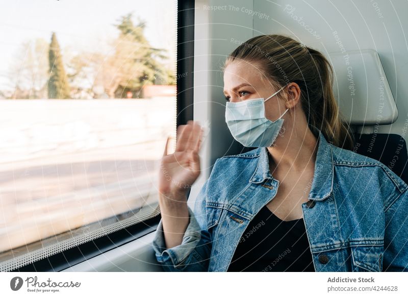 Woman in mask waving hand in window from train woman ride passenger wave hand greeting new normal gesture hello hi cheerful transport medical epidemic pandemic
