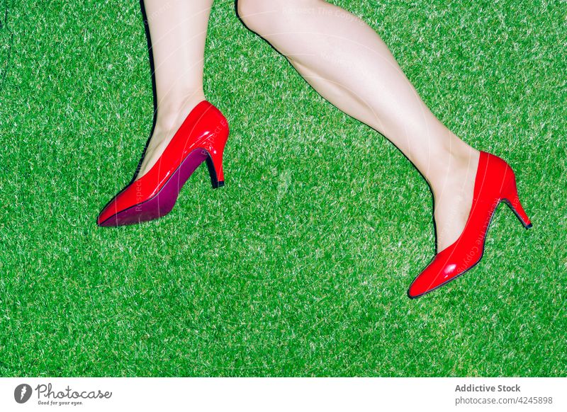 Woman in stylish red shoes lying on grass woman footwear fashion style lawn heel elegant cloth female meadow apparel garment colorful outfit feminine attire
