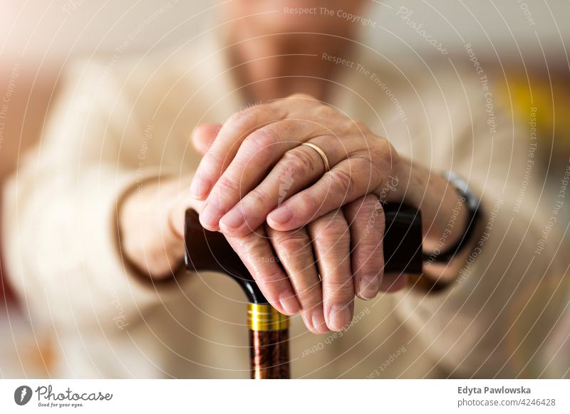Close-up of senior's hands leaning on walking cane people woman mature casual female Caucasian elderly home house care old health healthcare nursing home aging
