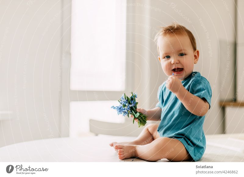 Spring portrait of a boy with a bouquet of flowers. The baby holds snowdrops in his hand and smiles child spring blue kid little love present adorable small