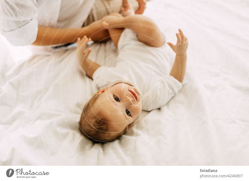 A charming baby is lying on the bed with his mother, mother and baby are resting together. Innocence, unity and family mom innocence togetherness son happy