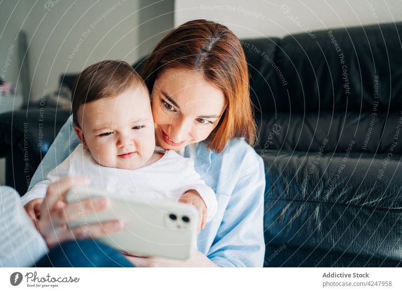 Mother and baby taking self portrait with mobile phone woman mother selfie smartphone together photo at home photography memory modern parent gadget device