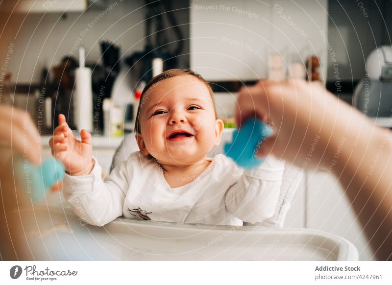 Adorable smiling baby sitting in highchair in kitchen feeding laugh smile content babyhood childcare eat cheerful adorable funny cute little joy mother sweet