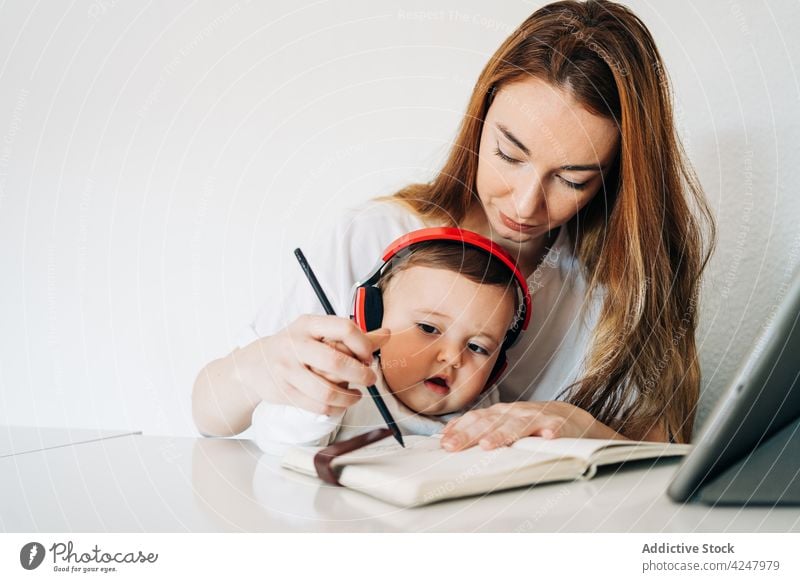 Mother teaching cute baby to write in copybook mother take note development learn together attentive casual sit diligent concentrate woman education adorable