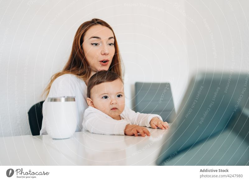 Mother and baby watching video on tablet mother together attentive entertain interest curious at home woman motherhood young casual little cute love parent