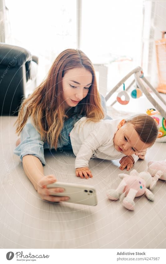 Mother and baby taking self portrait with mobile phone woman mother selfie smartphone playful together photo at home photography memory modern parent gadget