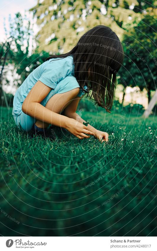 Kid squats in the garden and plays Playing Crouch Blue Turquoise out search explore Research Discover Exterior shot Summer Joy Child Infancy Nature Curiosity