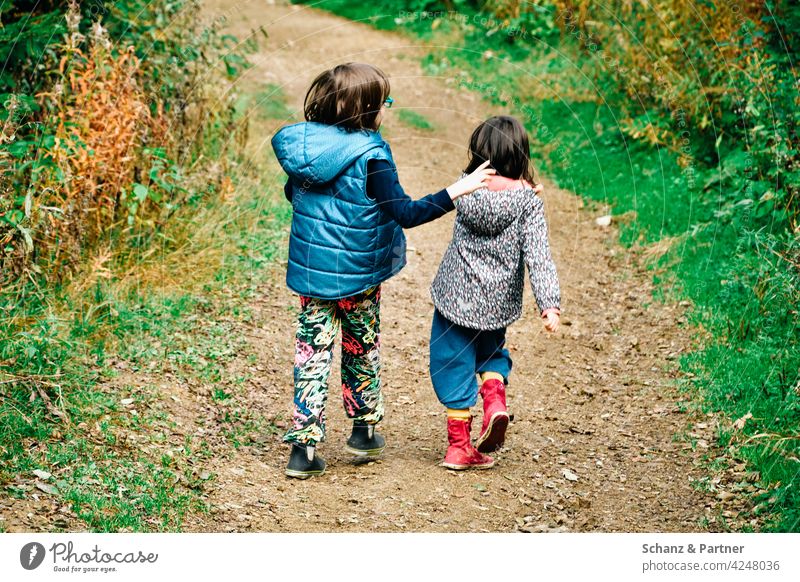two children strolling through the forest Hiking Friendship Walking Sisters at the same time Family out Nature Infancy Child Girl vacation hike Together Happy