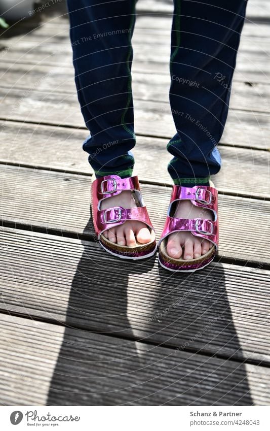 Kid with pink patent sandals Sandals Slippers Shadow wooden floorboards Balcony Summer Child Infancy Childlike Sheepish Toes feet Feet glitter Glittering