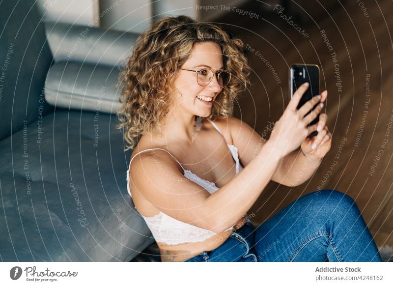 Positive young lady sitting on floor and taking selfie on smartphone woman smile positive self assured style social media home confident trendy chill female