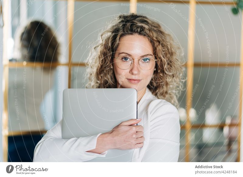 Stylish young female employee with laptop in hands woman self employed elegant confident job work workspace internet online human face curly hair blond