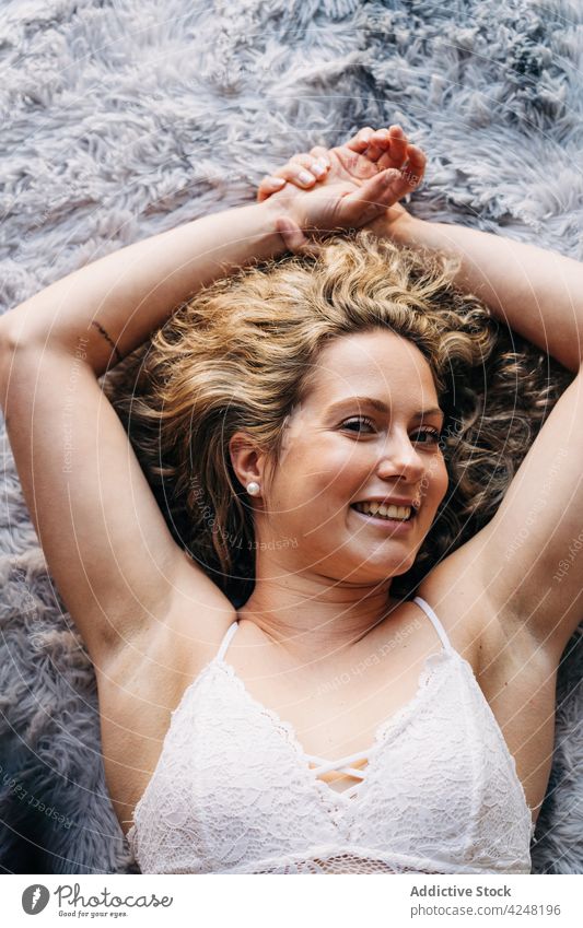 Relaxed young woman lying on carpet rest calm tranquil home serene chill feminine comfort appearance female blond curly hair bra jeans body allure cozy