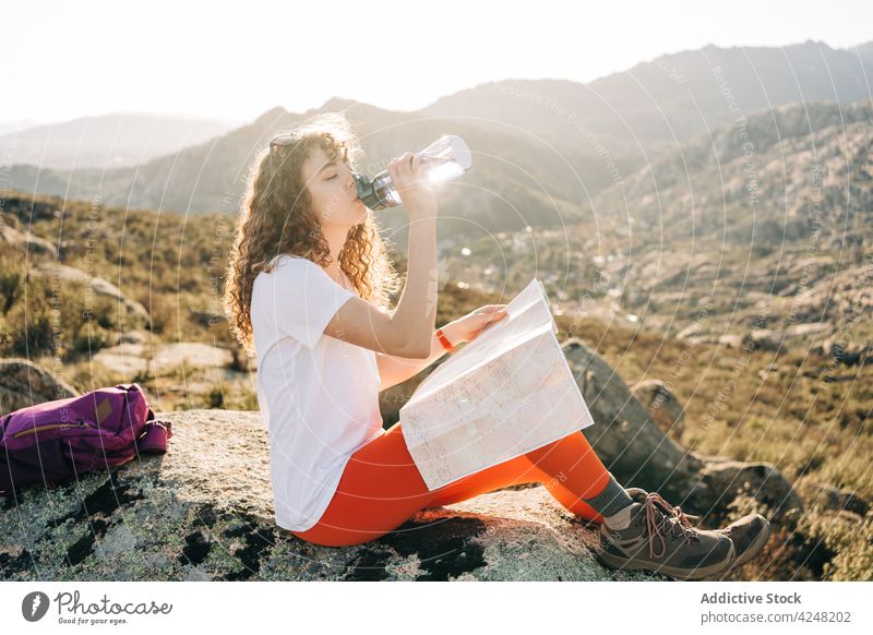 Young woman drinking water and reading map during hiking trip in highland mountain hiker trekking thirst traveler tired journey adventure nature orientate