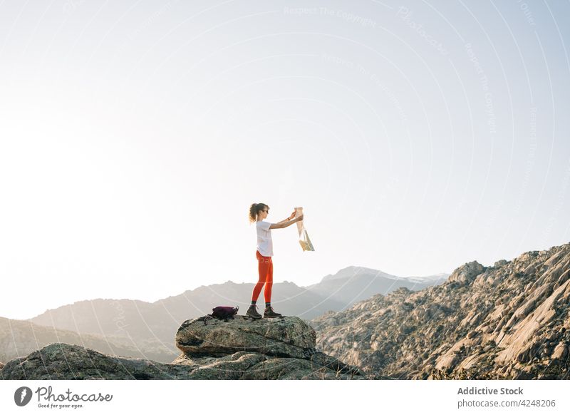 Young female traveler launching kite standing on rocky mountain peak woman nature hiker landscape enjoy valley picturesque young adventure freedom journey