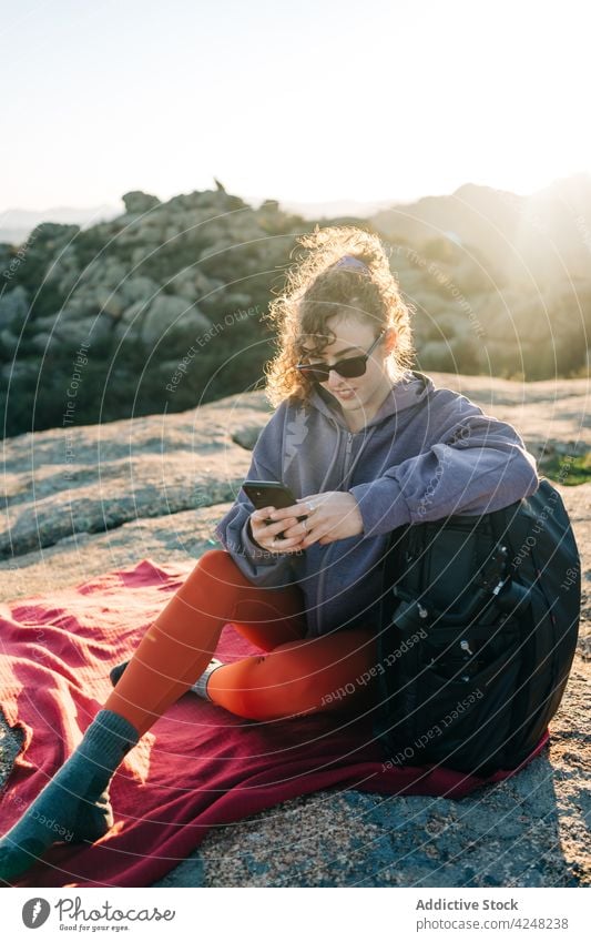 Happy young lady messaging on smartphone while resting on hill during trekking woman using hiker smile message explore joy positive happy relax female