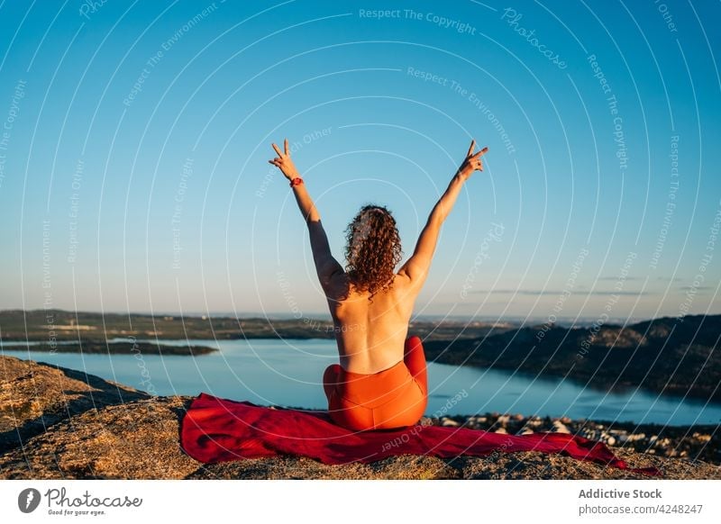 Fit topless woman showing V sign with raised arms on rocky mountain v sign happy traveler smile joy content positive town tourist enjoy female young curly hair