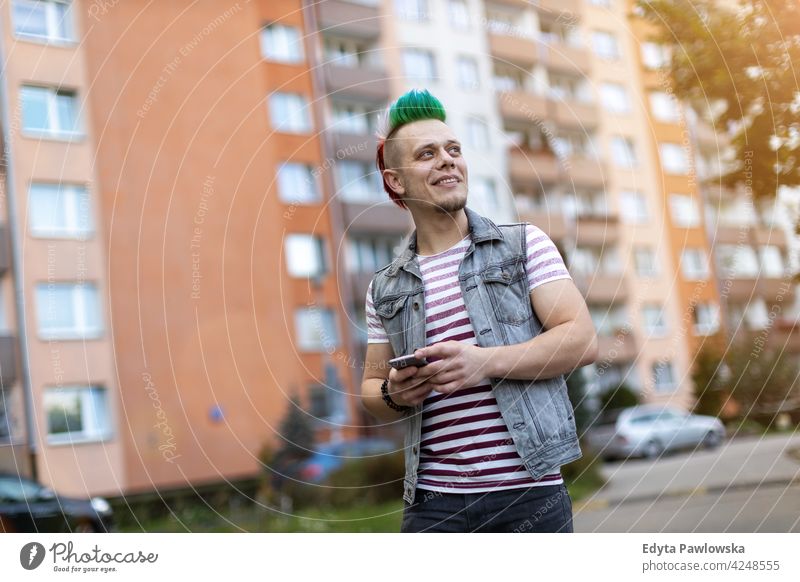 Young punk man with smart phone portrait adults young people one person casual teenage male alone trendy fashion cool mohawk hair colorful style stylish retro