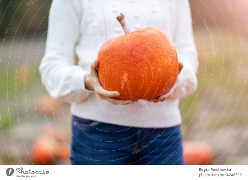Woman holding pumpkin in pumpkin patch field halloween nature park autumn fall woman adult young female people happy smiling fun caucasian enjoying outdoors