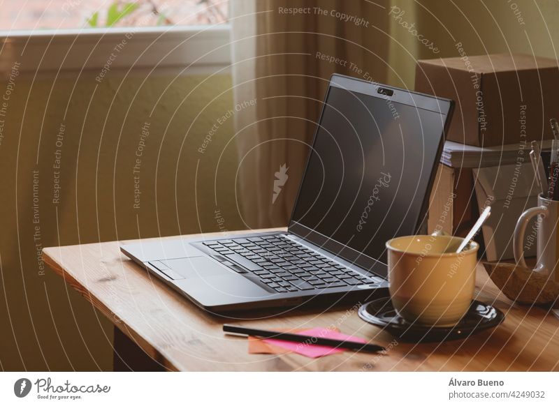 The home office, an example of a space for teleworking from home, where you can see a laptop and a cup of coffee or hot tea, early in the morning, in Madrid, Spain. Work-life balance.