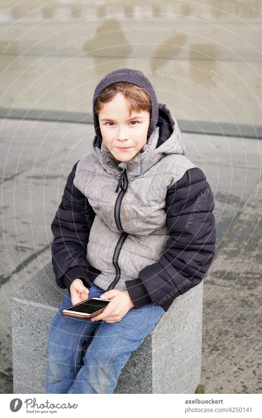 7 year old boy with smartphone outdoors in winter child kid mobile cell technology play game little people young internet childhood lifestyle person caucasian